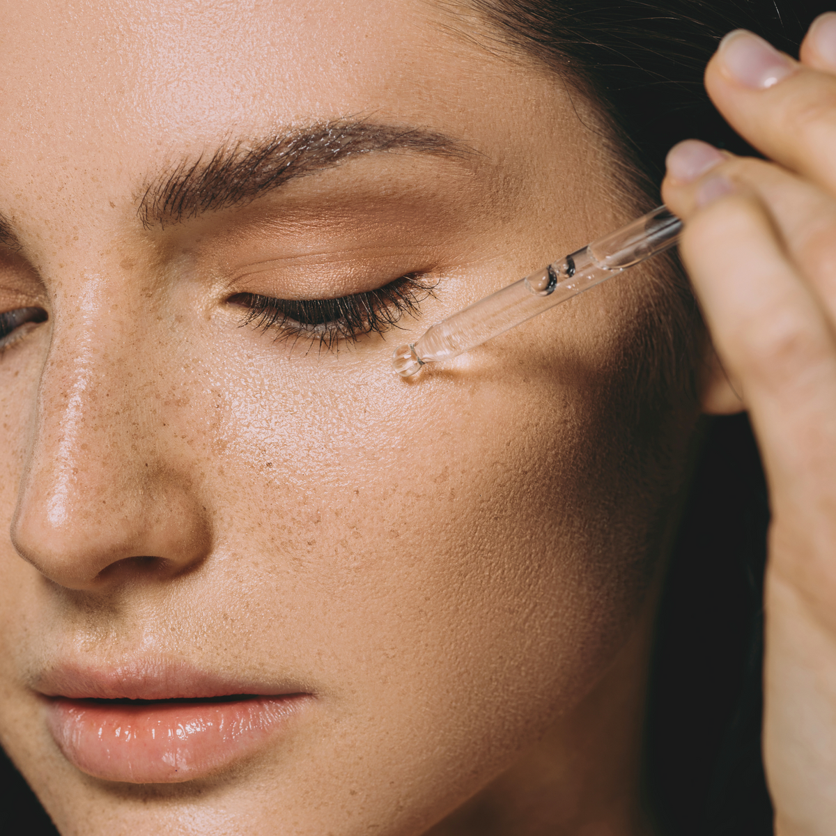 A woman applying Vitamin C serum to her face